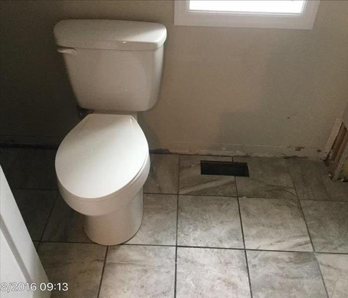 White toilet in tan bathroom with marble tile flooring