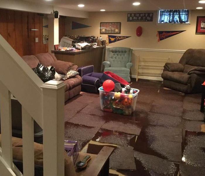 Room downstairs with water puddles on a maroon carpet