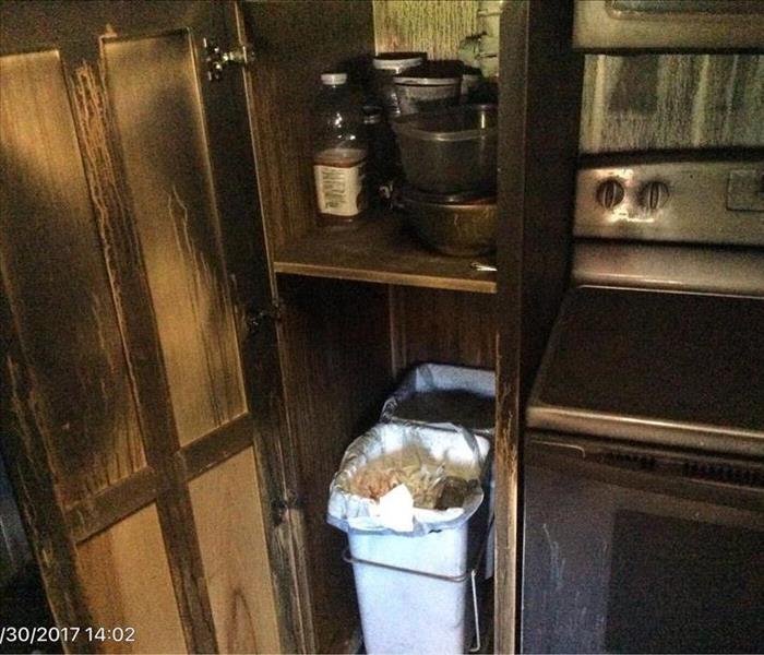 Wood cabinets and chrome stove with thick soot on the door and inside