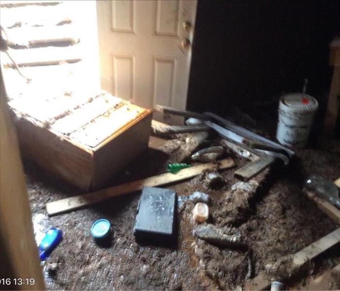 Dresser and other debris in mud and water at the bottom of basement steps